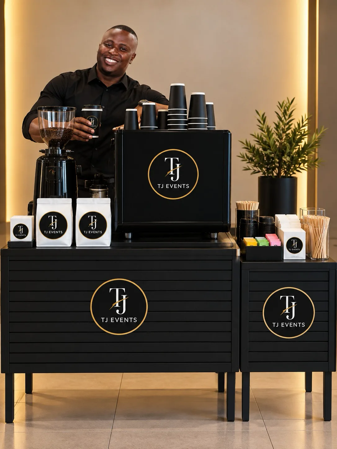 Smiling TJ Events barista behind a branded mobile coffee bar with professional machine, cups and condiments